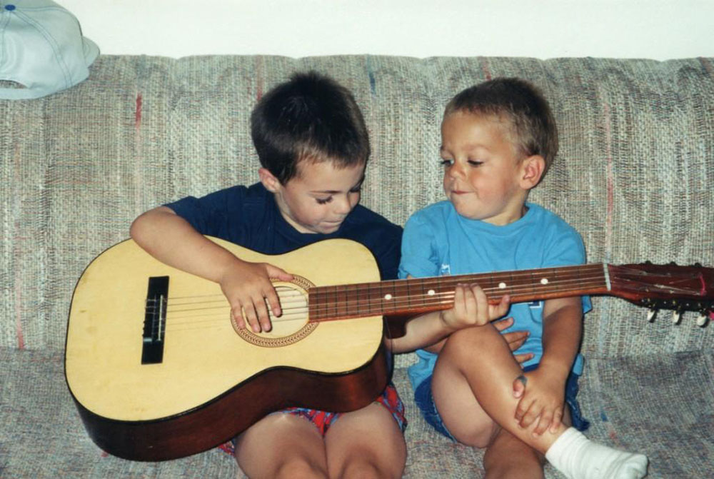 Young boys playing with a guitar.
